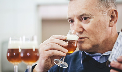 Man smelling beer in glass during sensory test