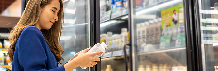 Woman reading dairy product label. Product pulled from supermarket fridge