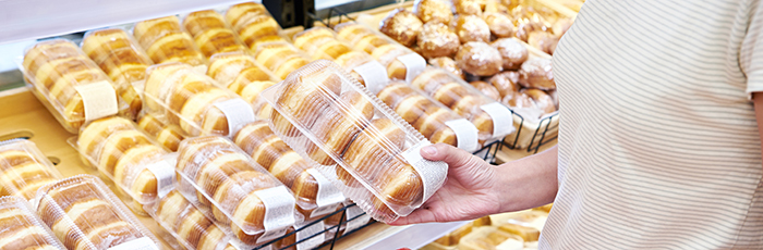 Shopper in supermarket picking up pack of doughnuts