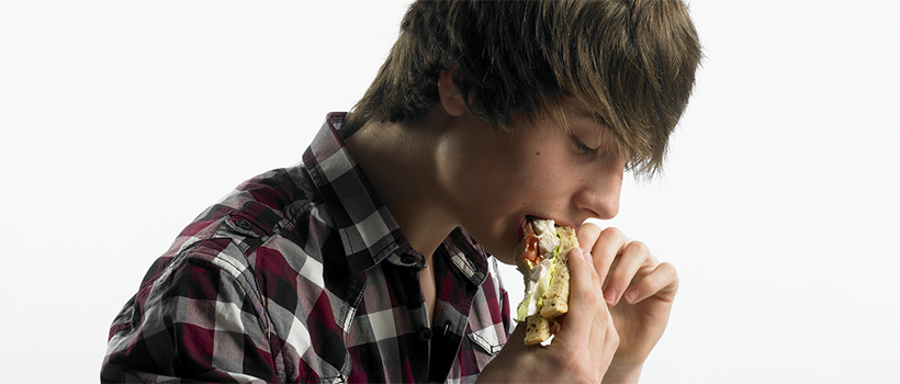Young man consuming a sandwich