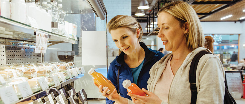 Shoppers comparing drinks at instore fridge