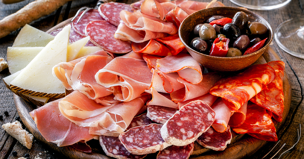 Cured meat selection on board with olives and cheese