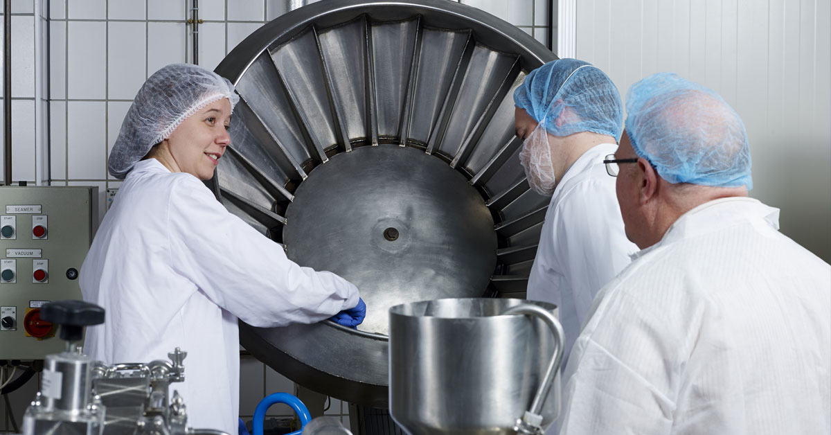 Factory working performing hygiene training demonstration on equipment