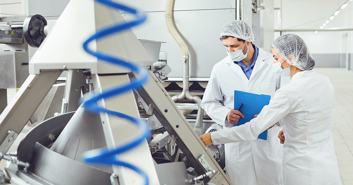 Man and woman inspecting equipment at a food factory