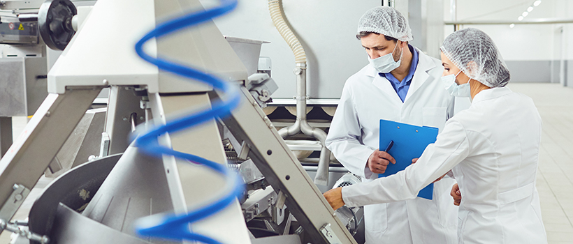 Factory workers inspecting equipment with clipboard