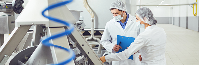 Factory workers inspecting equipment with clipboard