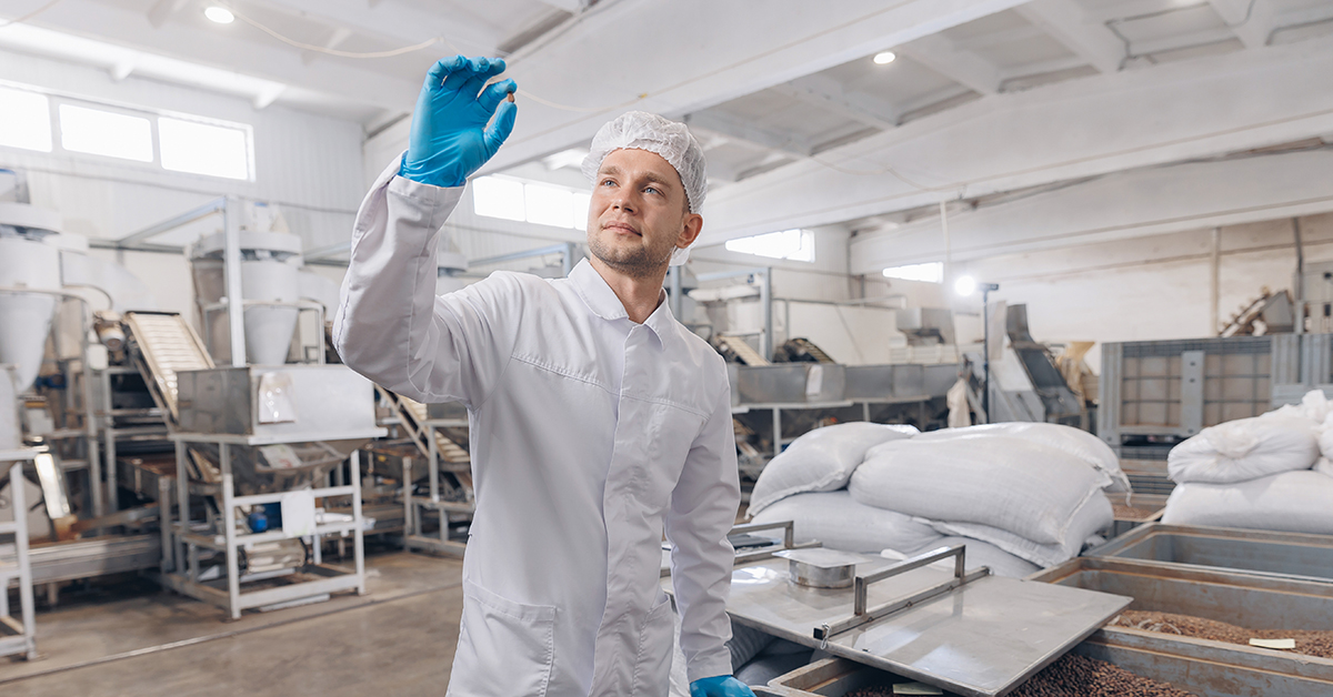 Factory worker inspecting food product from production line in factory