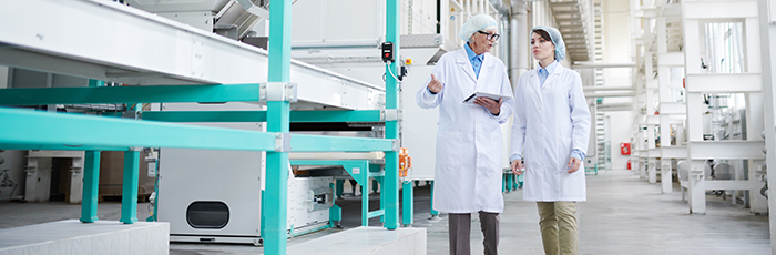 Factory workers walking through factory conducting audit