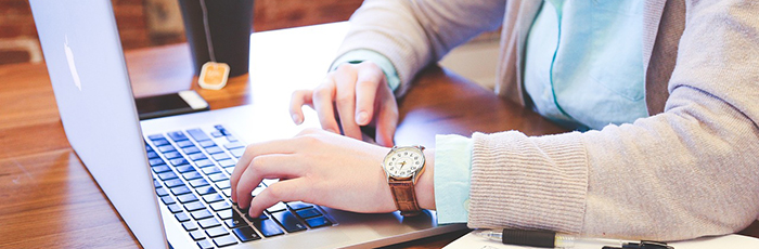 User at laptop with hot drink in background