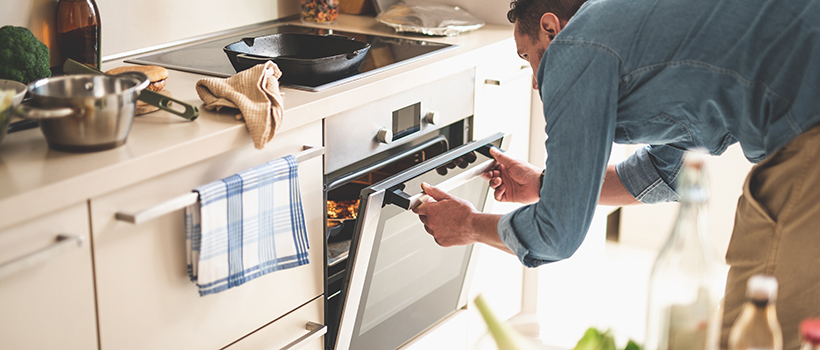 Man cooking dinner opening oven door