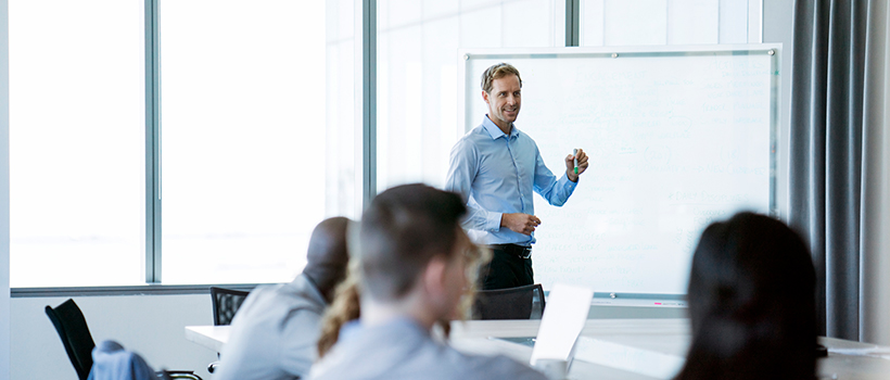 Man presenting in front of board to office