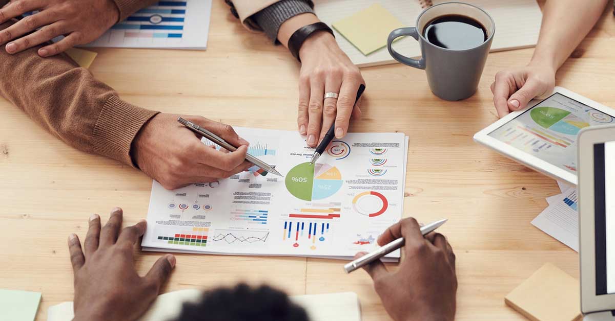 Business meeting with people discussing tactics and strategies with charts on paper