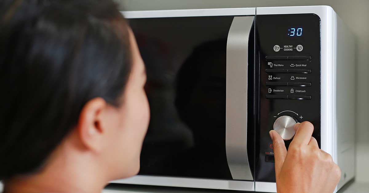 Woman turning dial setting on microwave