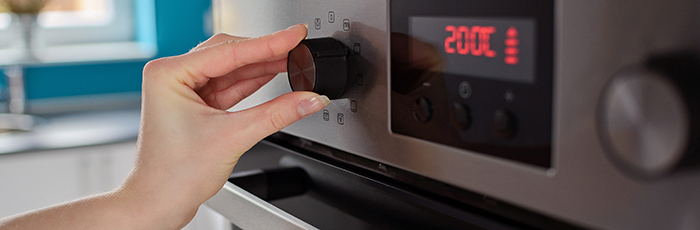 Person turning dial on an oven in kitchen