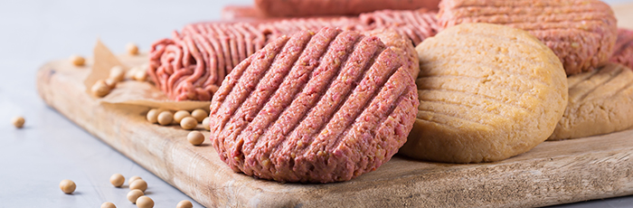 Plant-based meat alternative burgers and mince on chopping board