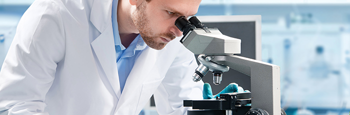 Scientist looking down a microscope