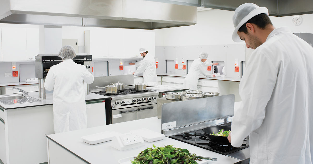 People preparing food in a kitchen with sensory booths attached