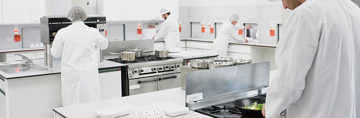 People preparing food in a kitchen with sensory booths attached