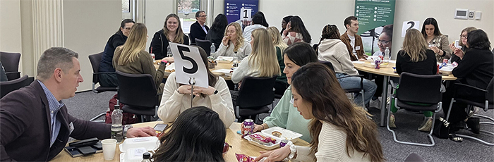 Students networking around tables in seminar room