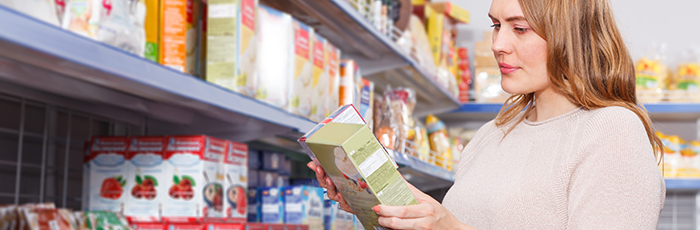 Woman in supermarket reading food packaging and comparing two food products