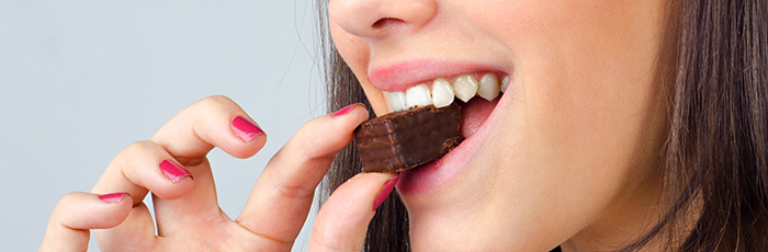 Woman biting a small chocolate