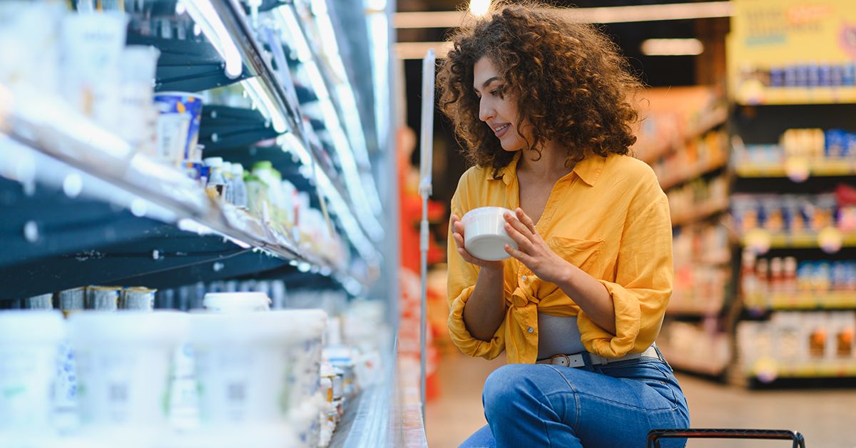 Woman in supermarket picking up yoghurt from fridge