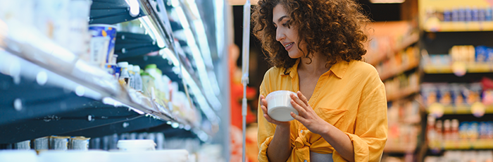 Woman in supermarket picking up yoghurt from fridge