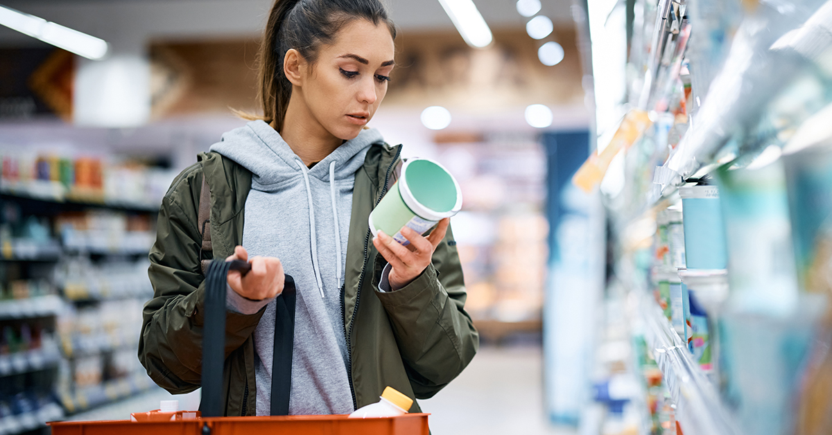 Woman reading dairy product label. Product pulled from supermarket fridge