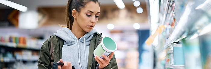 Woman reading dairy product label. Product pulled from supermarket fridge